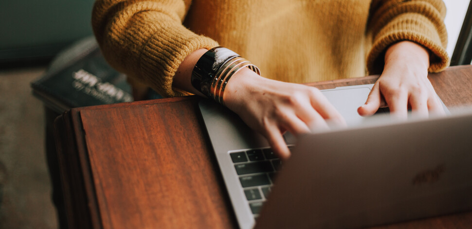 Obrazek przedstawia osobę pracującą przed laptopem.