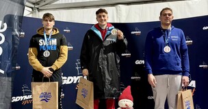 Three students standing on a sports podium wearing medals, representing individual academic or athletic success.