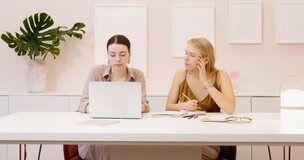 dwie dziewczyny siedzące przed komputerem