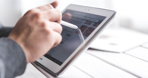 Obrazek przedstawia osobę pracującą na tablecie.