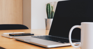 laptop na blacie obok kubek