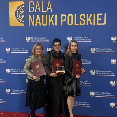 Autorki publikacji na tle baneru Gala Nauki Polskiej. Baner jest granatowy, napis jest złoty, a dodatkowo rozmieszczone jest logo Ministerstwa Nauki i Szkolnictwa Wyższego.