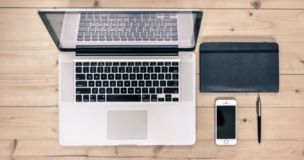 laptop, notebook and phone lay down on the desk
