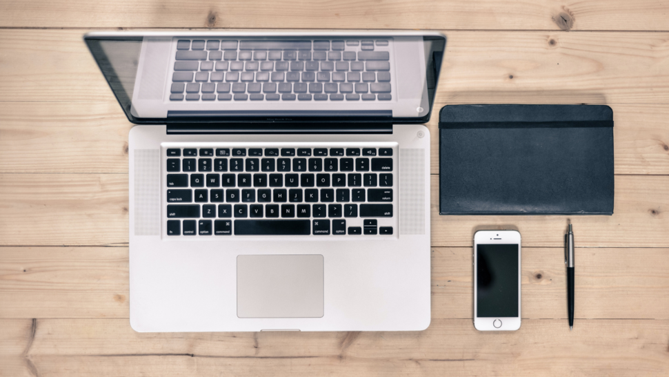 laptop, notebook and phone lay down on the desk