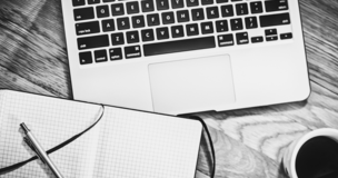 na biurku leży laptop, notatnik i długopis