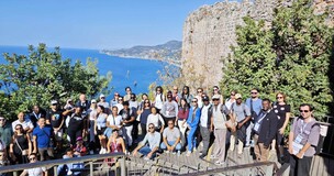 Students and lecturer gathered on a rocky hill with the sea in the background during a study visit to Turkey.