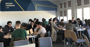 Students seated at tables in a modern classroom, participating in a workshop session for the INTQUANT project.