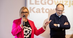 Dagmara Piskorz and Bartłomiej J. Gabryś - Two presenters speaking into microphones in front of a screen during Creativity Week activities. 