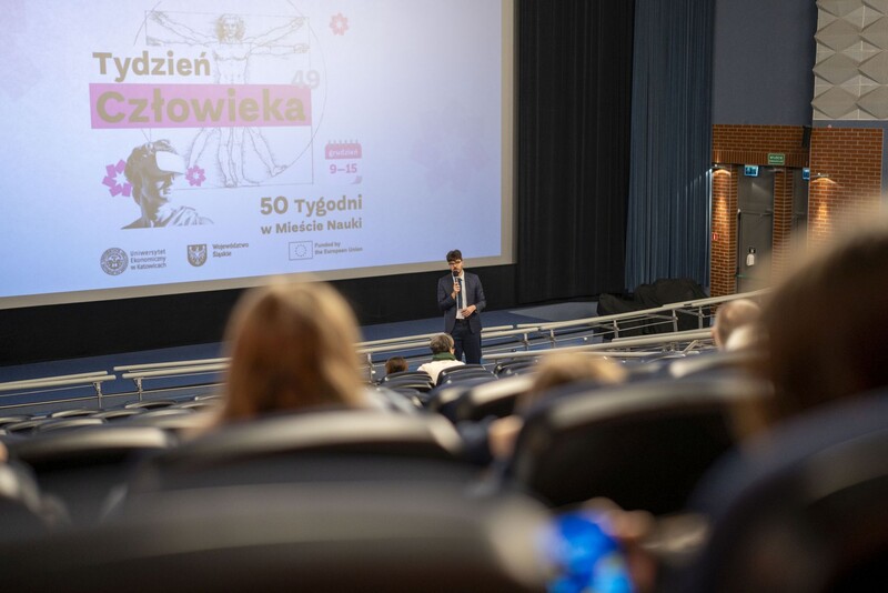 zdjęcie wykonane podczas Tygodnia Człowieka w Mieście Nauki; jeden z prelegentów mówiący do uczestników siedzących w Kinie Kosmos