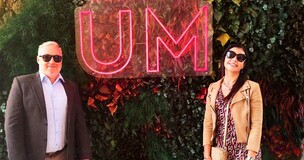 Two university representatives standing inf front of the green background 