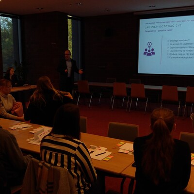 Uczestnicy projektu Akademia Kariery, siedzą przy stolikach i słuchają prelegenta