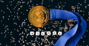 medal na ciemnym tle, napis "winner" ułożony z kostek