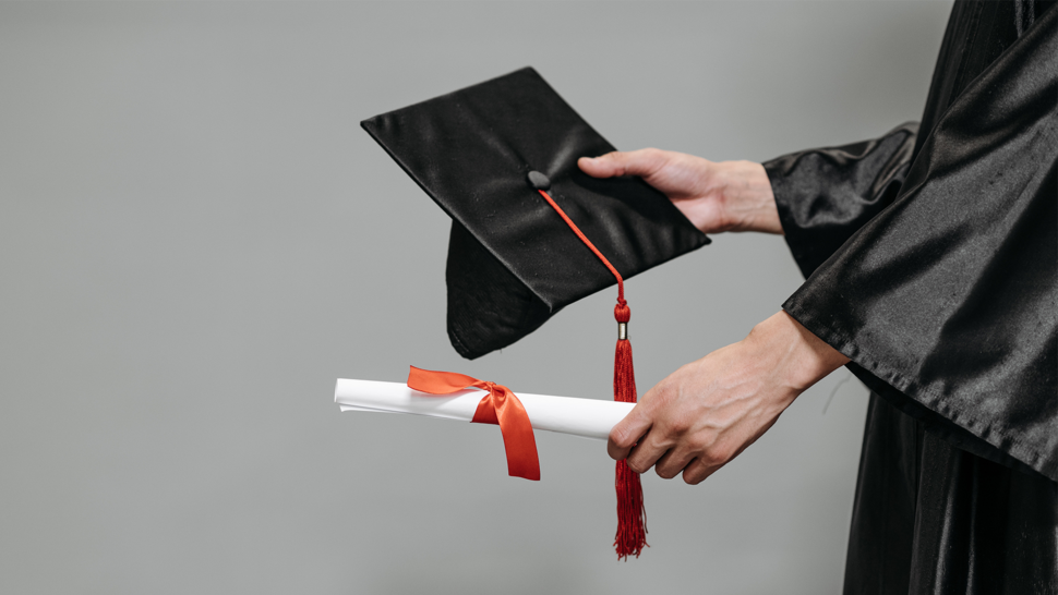 Zdjęcie czapki absolwenckiej i rulonu papieru zawiniętego kokardką