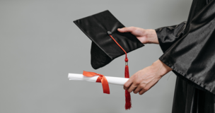 Zdjęcie czapki absolwenckiej i rulonu papieru zawiniętego kokardką