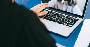 Webinarium na temat bezpieczeństwa w biznesie - grafika ilustrująca przedstawia fragment laptopa i osobę robiącą notatki