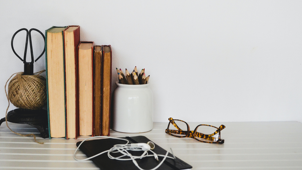 Książki, okulary i słuchawki na biurku