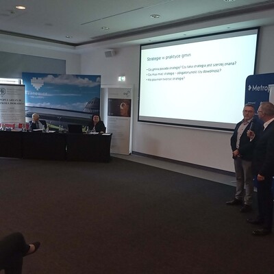 dwie osoby prowadzące wykład z wyświetloną prezentacja multimedialną