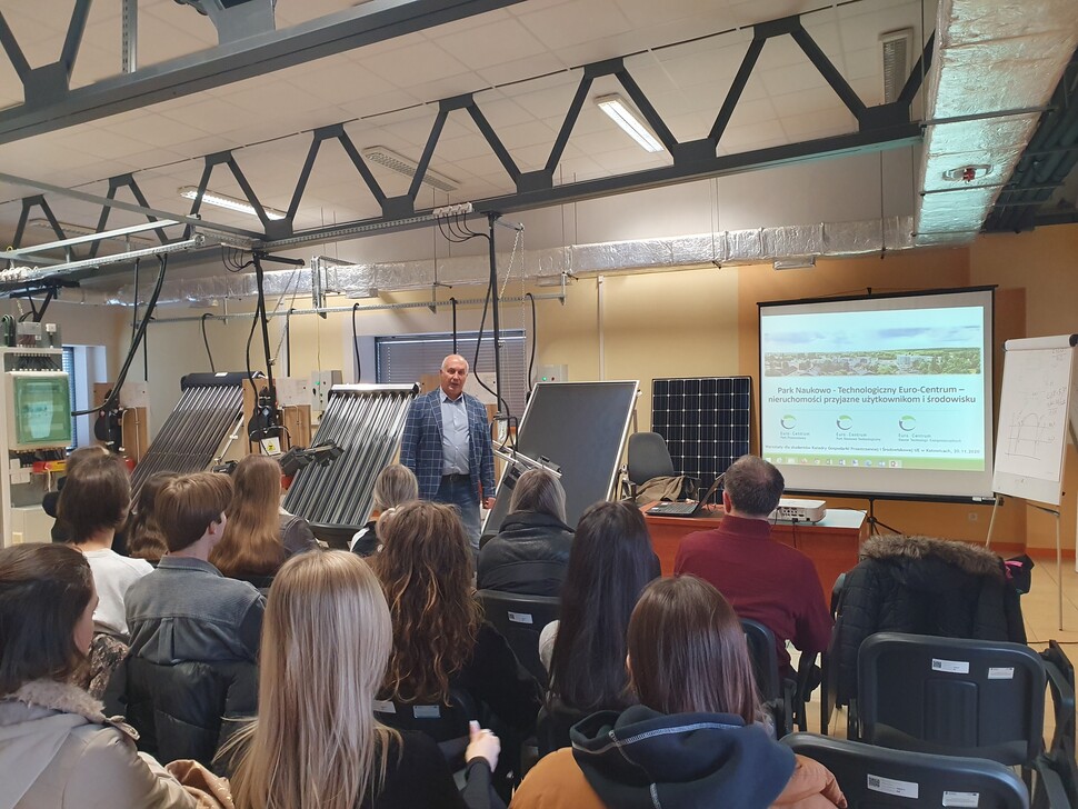 Studenci siedzący w sali i wysłuchujący wystąpienia przedstawiciela Euro-Centrum. Widok z tyłu sali, w tle prezentacja.