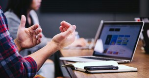 męska sylwetka siedząca przed laptopem, gestykulująca rękami