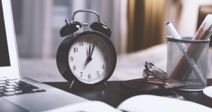 kawałek laptopa, zeszyt oraz zegar