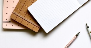 notesy w lewym górnym rogu, w dolnym prawym dwa długopisy
