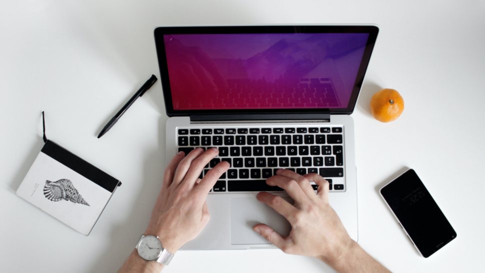 laptop na biurku z pomarańczą