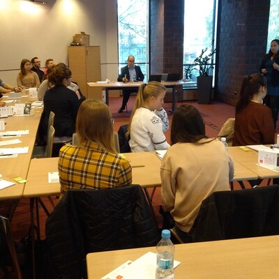 Uczestnicy projektu Akademia Kariery, siedzą przy stolikach i słuchają prelegenta