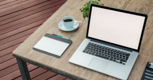 One the desks are laptop, notebook and mug with cofee