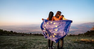 Fotografia prezentująca dwie osoby z flagą Unii Europejskiej