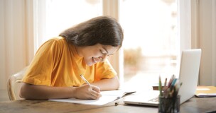 Obrazek przedstawia notującą studentkę