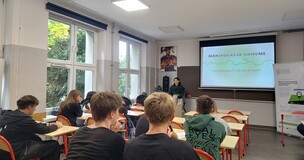 Fotografia przedstawia zajęcia edukacyjne w sali lekcyjnej, podczas których prowadząca omawia manipulację danymi. Na ekranie widnieje tytuł „MANIPULACJA DANYMI”, a uczniowie siedzą przy ławkach i słuchają prezentacji; po prawej stronie znajduje się stojak informacyjny.