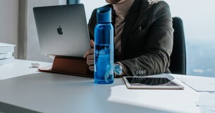 mężczyzna siedzący przy biurku z komputerem i tabletem