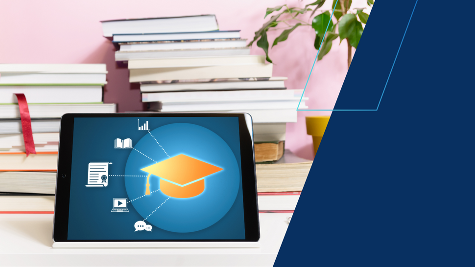 Tablet stojący na biurku wyświetla ikonę czapki absolwenta otoczoną symbolami nauki (książka, wykres, certyfikat, wideo, czat).