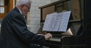 Pianist playing in a concert hall with sheet music on a grand piano during “The Ogiriskis” salon performance.