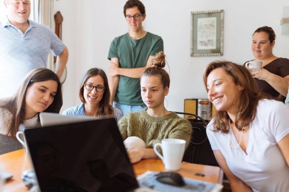 a group of people sitting in front of a computer