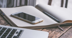 computer, phone and notes lay down on the desk