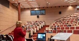 zdjęcie wykonane z tyłu prelegenta, w tle uczestnicy siedzący na Auli