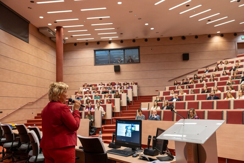 zdjęcie wykonane z tyłu prelegenta, w tle uczestnicy siedzący na Auli