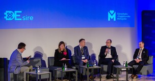Experts seated on a stage panel under spotlights at the Repower World Summit, with event branding in the background.