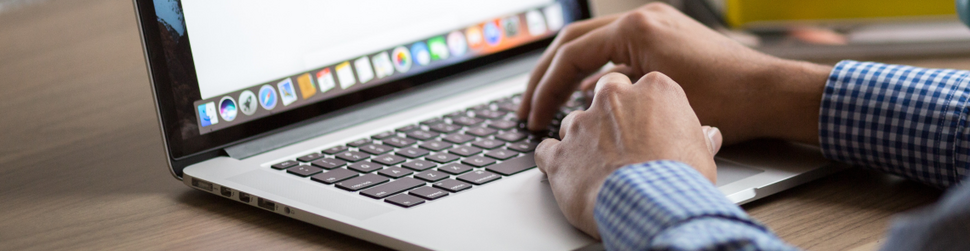 Obrazek przedstawia fragment laptopa i dłonie piszące na klawiaturze