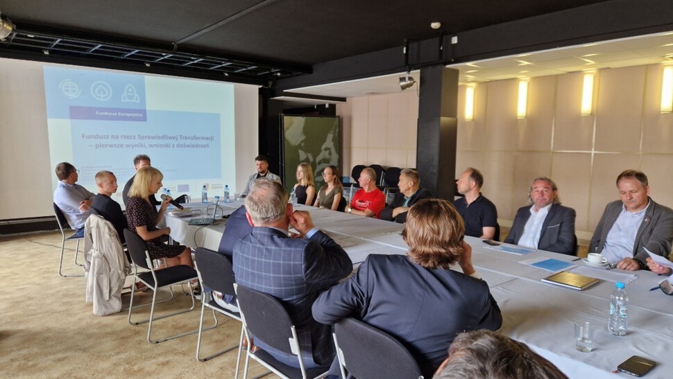 Zdjęcie prezentujące grupę uczestników przy stole konferencyjnym. 