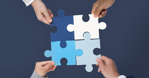 cztery ręce trzymające po jednym puzzlu