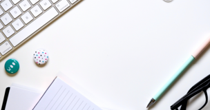 klawiatura, długopisy i okulary leżące na biurku