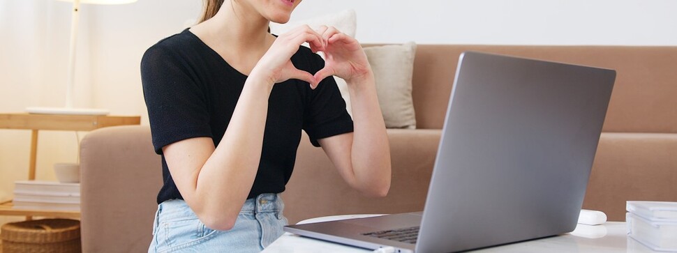 kobieta przed laptopem układająca dłonie w kształt serca
