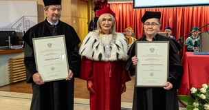 University staff in academic regalia presenting honorary professor diplomas on stage during a formal event.