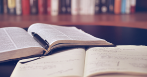 Na biurku leży książka, długopis i zeszyt