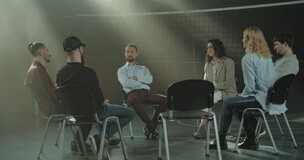 Obrazek przedstawia ludzi siedzących na krzesłach i rozmawiających - forma terapii