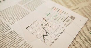 Rozłożone gazety i dokumenty finansowe z widocznym wykresem liniowym