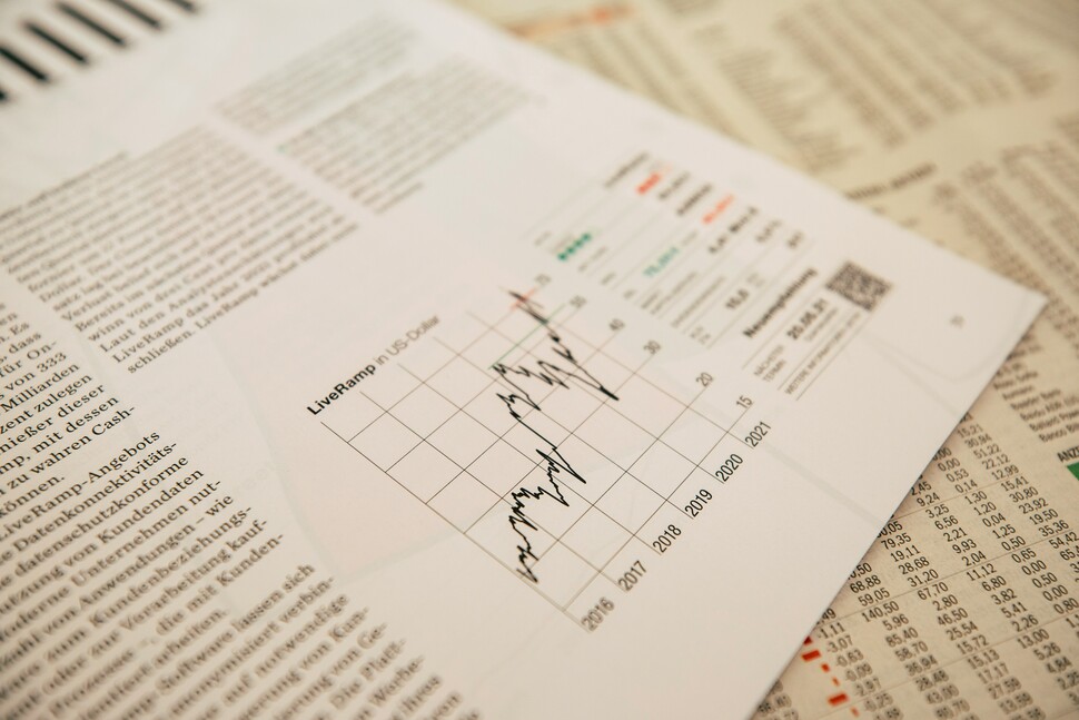 Rozłożone gazety i dokumenty finansowe z widocznym wykresem liniowym