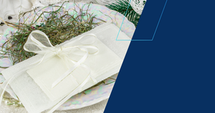 Biały opłatek przewiązany ozdobną, kremową wstążką leży na talerzu udekorowanym siankiem świątecznym; w tle białe, bożonarodzeniowe ozdoby i gałązki świerku. Po prawej stronie znajduje się duże, granatowe pole graficzne.